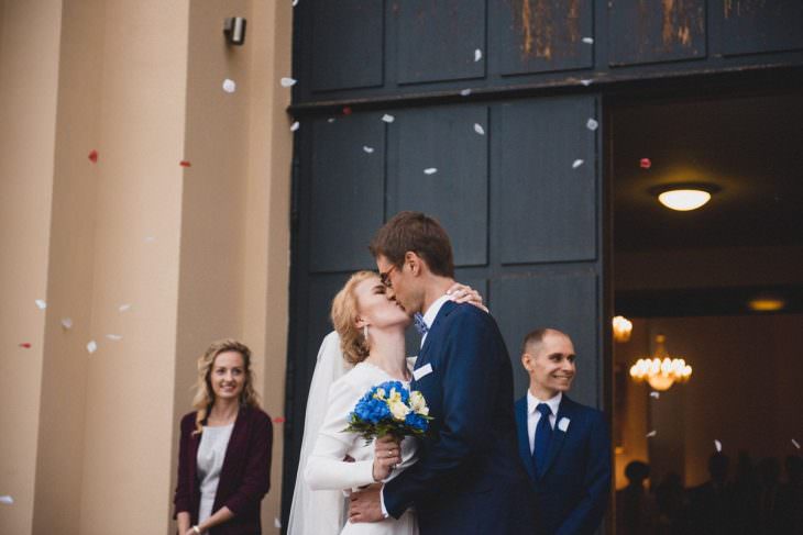 bride and groom kisses in front of the church flowers in the air