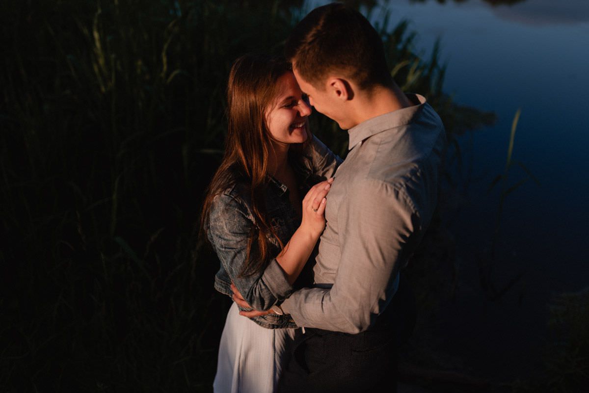 the couple is smiling on the lake at sunset it gets dark
